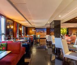 Restaurante elegante com mesas postas, cadeiras brancas e iluminação suave.