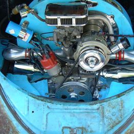 Car engine with multiple components in a blue vehicle compartment.