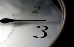 Nahaufnahme einer Uhr mit schwarzem Zeiger, der knapp nach der Zahl 3 zeigt.