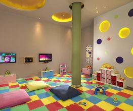 Sala de juegos infantil con alfombra colorida, cojines y pantallas en las paredes.