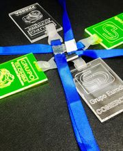 Cuatro identificadores de plástico transparente y verde con cintas azules sobre una superficie negra.