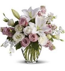 Vaso com flores brancas e rosas, incluindo lírios e rosas, em arranjo elegante.