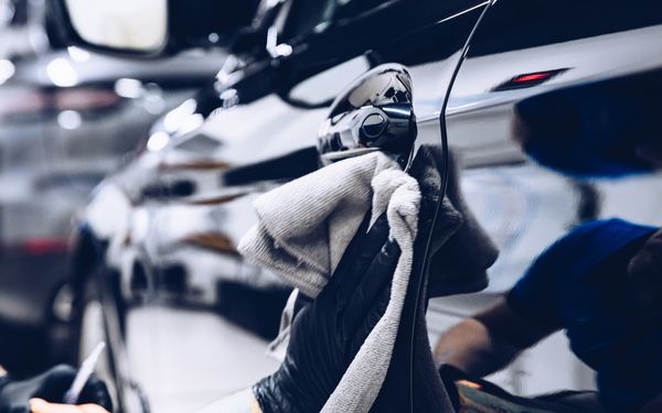 Nahaufnahme einer Autopolitur mithilfe eines Mikrofasertuchs.