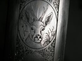 Graviertes Hirschmotiv auf Metall in detailliertem, dekorativem Rahmen.