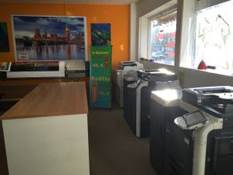 Druckerei mit Kopiergeräten und Postern, leere Theke und Werbeplakate für X-Banner und Roll-Up.