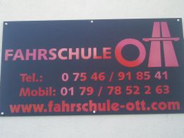 Schwarzes Schild mit der Aufschrift "Fahrschule Ott" und Kontaktinformationen in Rot.