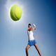 Tennis player hitting a ball mid-air under a bright sun in the blue sky.