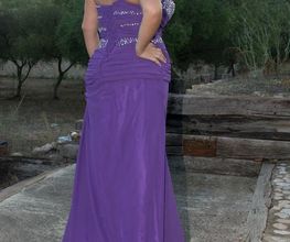 Mujer con vestido púrpura posando de espaldas en un entorno natural con árboles al fondo.