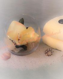 Glasvase mit gelber Blume, gelbes Handtuch und Muscheln auf Sand.