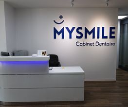 Empfangsbereich einer Zahnarztpraxis mit "MYSMILE" Logo an der Wand.