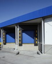 Lagerhaus mit blauen Laderampen bei sonnigem Wetter.