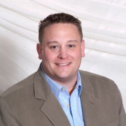 Smiling man in a suit with a white backdrop.