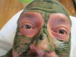 Person mit grüner Gesichtsmaske entspannt sich auf einem Handtuch.