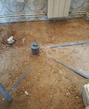 Pisos de tierra y tuberías grises en una habitación sin terminar, con radiador al fondo.