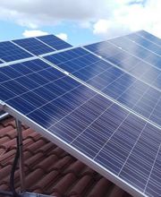 Paneles solares sobre un techo, con cielo azul y nubes en el fondo.