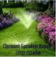 Lawn with sprinklers and colorful flowers, "Clermont Sprinkler Repair" and phone number text.