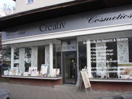 Außenansicht eines Kosmetikstudios mit Schaufenstern und einem Schild mit Behandlungsangeboten.