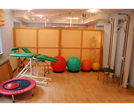 Fitnessraum mit Gymnastikbällen, Trampolin, Behandlungsbank und Fitnessgerät.