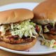 Twee hamburgers met koolsla op een wit bord.
