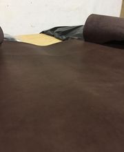 Un rollo de tela marrón extendido sobre una superficie, listo para cortar.