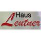 Logo mit der Aufschrift "Haus Leutner" in schwarzer und roter Schrift auf hellem Hintergrund.
