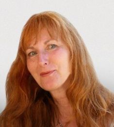 Eine Person mit langen, roten Haaren lächelt freundlich in die Kamera.