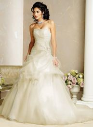 Sposa in abito bianco elegante con gioielli, vicino a colonne e fiori in un interno raffinato.