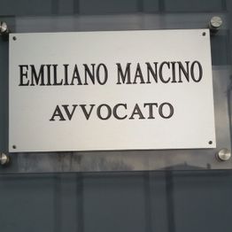 Targa con scritto: "Emiliano Mancino Avvocato" su sfondo metallico.