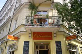 Gelbes Gebäude mit Balkon und Schildern für Bar, Restaurant und Zimmervermietung, namens "Freiraum".