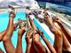 Frauen entspannen am Pool mit Sektgläsern, während sie stilvolle, weiße Sandalen tragen.