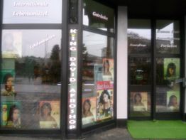 Schaufenster eines Afroladens mit Postern von Frauen und der Aufschrift „Internationale Lebensmittel“.