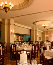 Restaurante elegante con mesas preparadas y lámparas de araña. Ambiente clásico y acogedor.