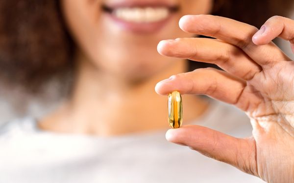 Eine Frau Hält eine Kapsel mit Omega-3-Fettsäuren zu Nahrungsergänzung in der Hand.