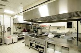 Commercial kitchen with stainless steel equipment and cooking appliances.