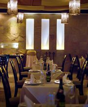 Restaurante elegante con mesas vestidas y lámparas colgantes, ambiente cálido y acogedor.