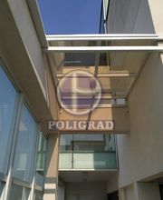 Cobertura de vidro entre prédios, refletindo céu azul.