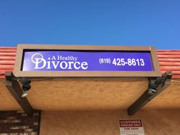 Sign for "A Healthy Divorce" with phone number, set against a clear blue sky.