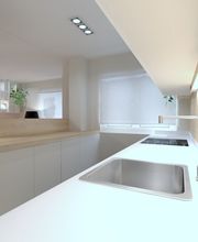 Cocina moderna con encimera blanca, fregadero, vitrocerámica y luces empotradas en el techo.