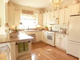 Bright kitchen with white cabinets, wooden floor, and natural light from a large window.