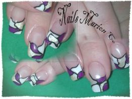 Bunte Nagelkunst mit lila, weißen und goldenen Mustern auf einer Hand.