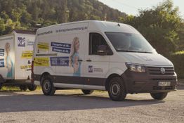 Weiße Transporter mit Aufschrift von KP Transportvermietung auf einer sonnigen Straße.