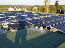 Solarpaneele auf einem Flachdach mit umliegender Landschaft im Hintergrund.