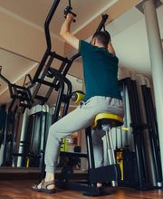 Person im Fitnessstudio beim Training an einem Gerät.