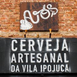 Placa de "Cerveja artesanal da Vila Ipojuca" em parede de tijolos.