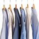 Several dress shirts on hangers, featuring various shades of blue and patterns.