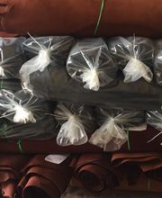 Rollos de tela marrón y negra apilados con extremos envueltos en plástico transparente.