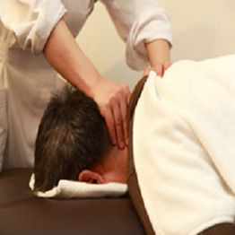 Person receiving a neck massage while lying face down on a massage table.