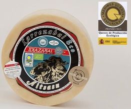 Queso Idiazabal ecológico premiado, con etiquetas de certificación y premio destacado al lado.