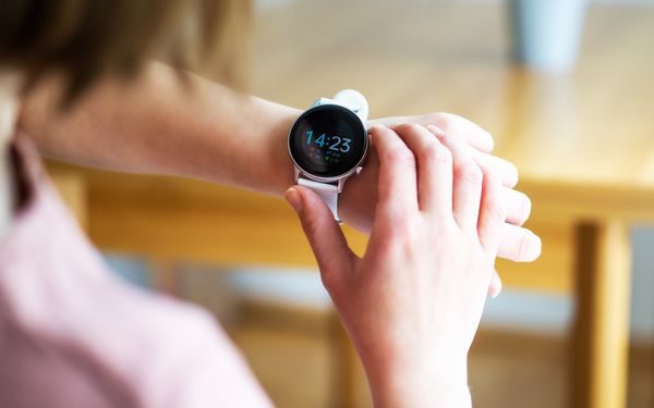 Frau trägt Fitness-Armband-Uhr und schaut auf die Uhrzeit