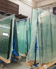 Große Glasplatten auf Rollwagen in einer Lagerhalle, bereit für den Transport.